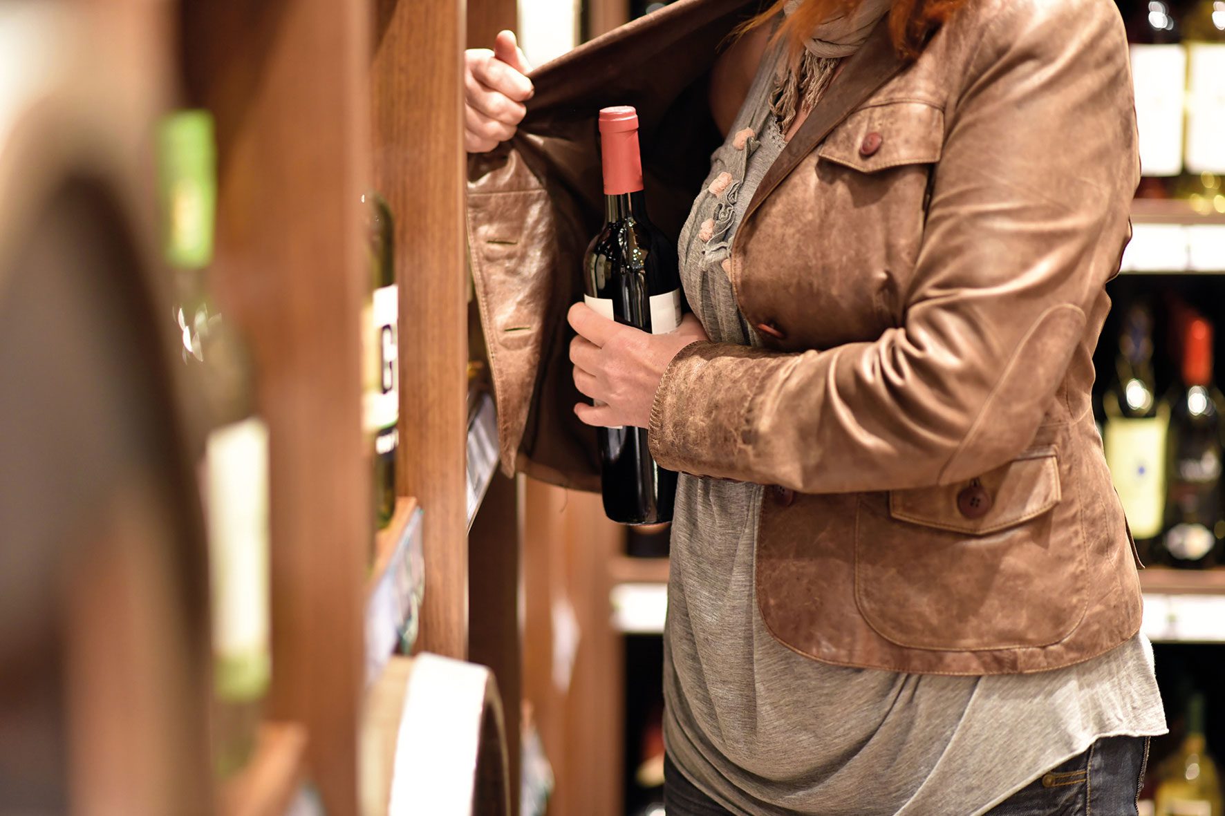 woman putting bottle in jacket