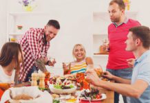 Men and women sat around a dinner table enjoying wine and variety of meals.