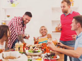 Home gatherings drive performance Men and women sat around a dinner table enjoying wine and variety of meals.