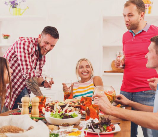 Home gatherings drive performance Men and women sat around a dinner table enjoying wine and variety of meals.