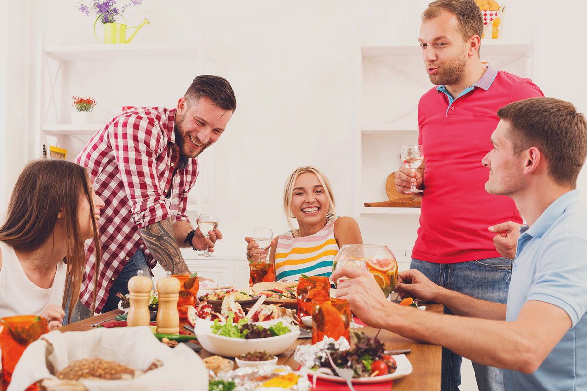 Men and women sat around a dinner table enjoying wine and variety of meals