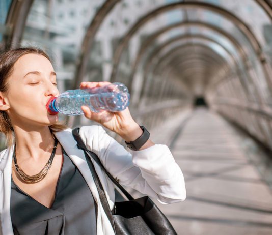 On the go is coming back Woman drinking water from bottle