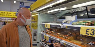 Man wearing mask in supermarket aisle