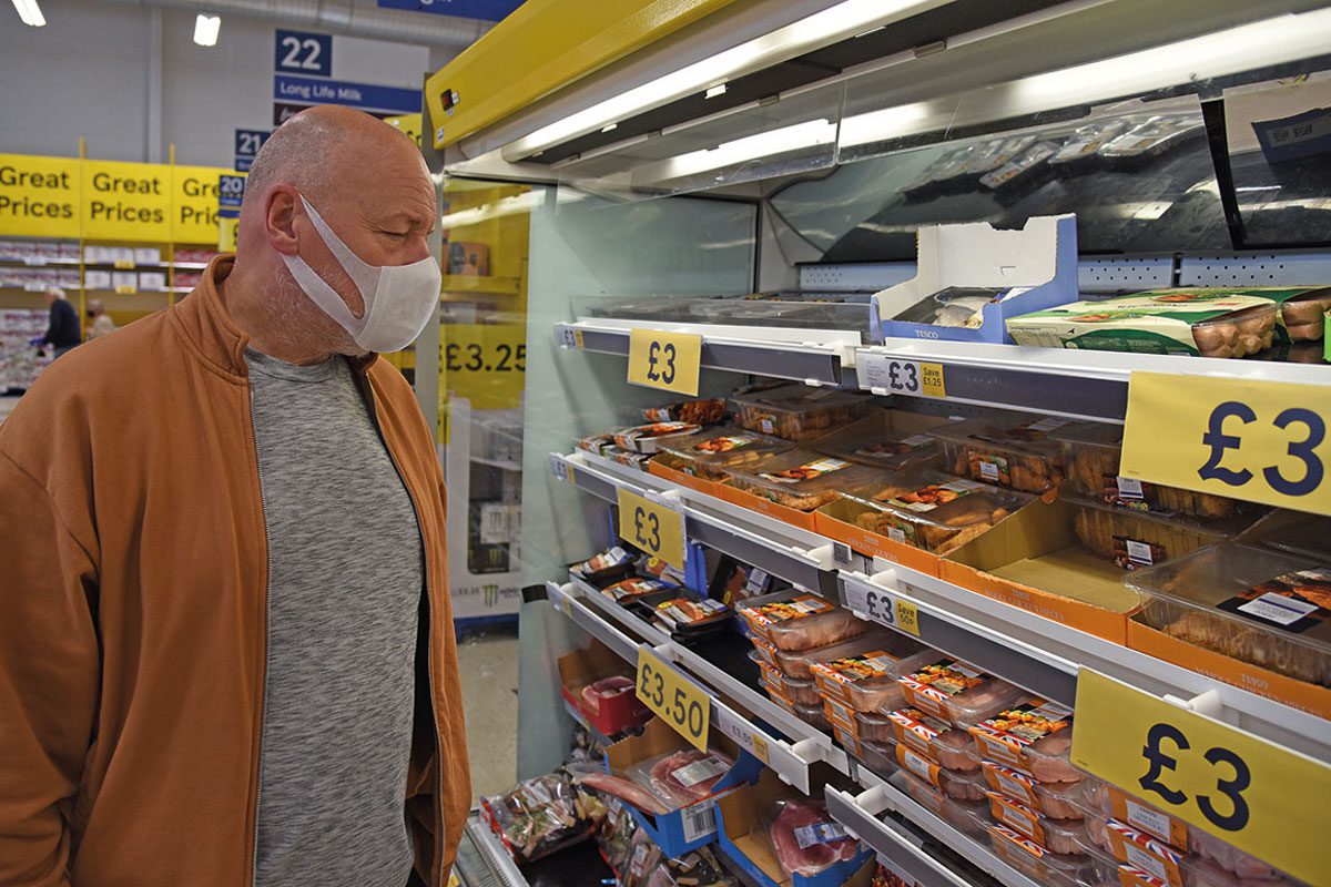 Man wearing mask in supermarket aisle