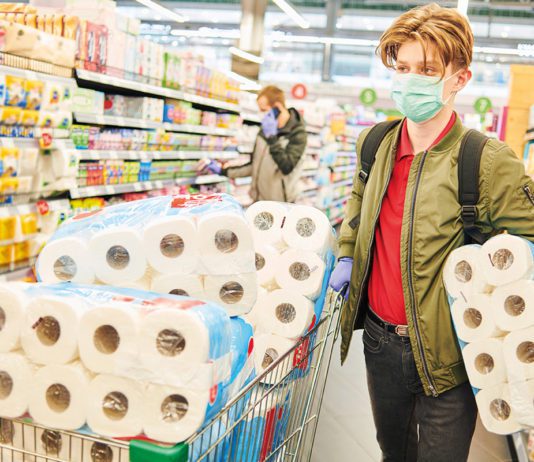 Thriving despite cost pressures person in supermarket with lots of toilet/kitchen paper