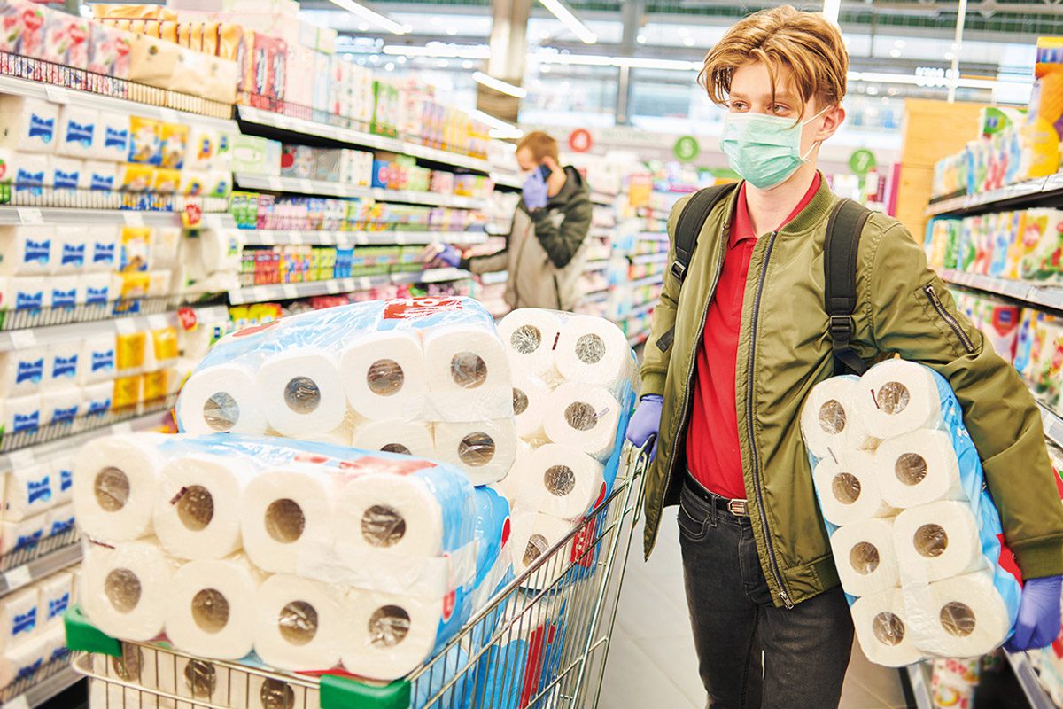 person in supermarket with lots of toilet paper