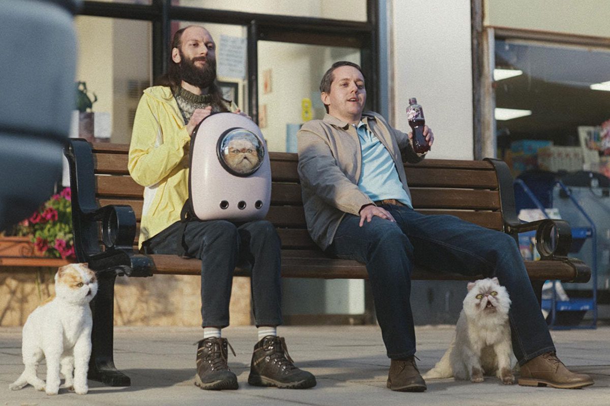 men sitting on a bench drinking Ribena