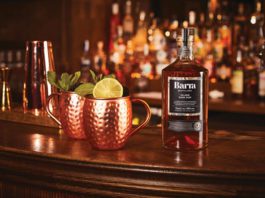 Island rum rolling out A bottle of dark rum next to two copper tankards
