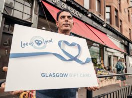 Loves Local new record A man hold a large loves local gift card outside a store front