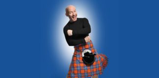 Image of comedian Craig Kelly wearing a black top and orange and blue kilt.