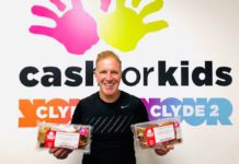 George bowie holds packets of mcghees cakes infront of cash for kids sign