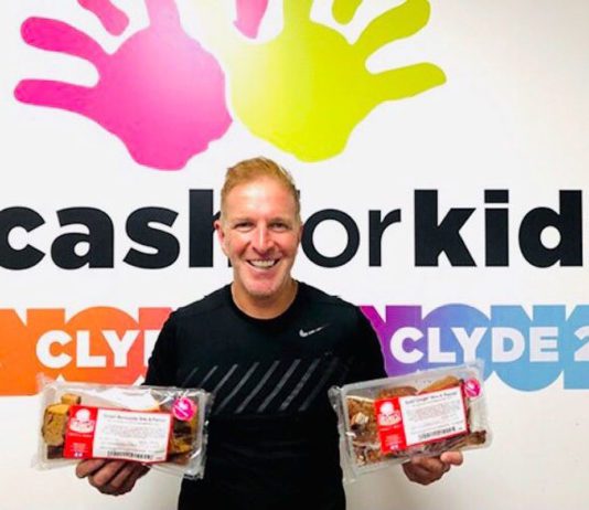 Innovative fundraising George bowie holds packets of mcghees cakes infront of cash for kids sign