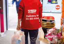 a snappy shopper deliver person carries two shopping bags out of a store