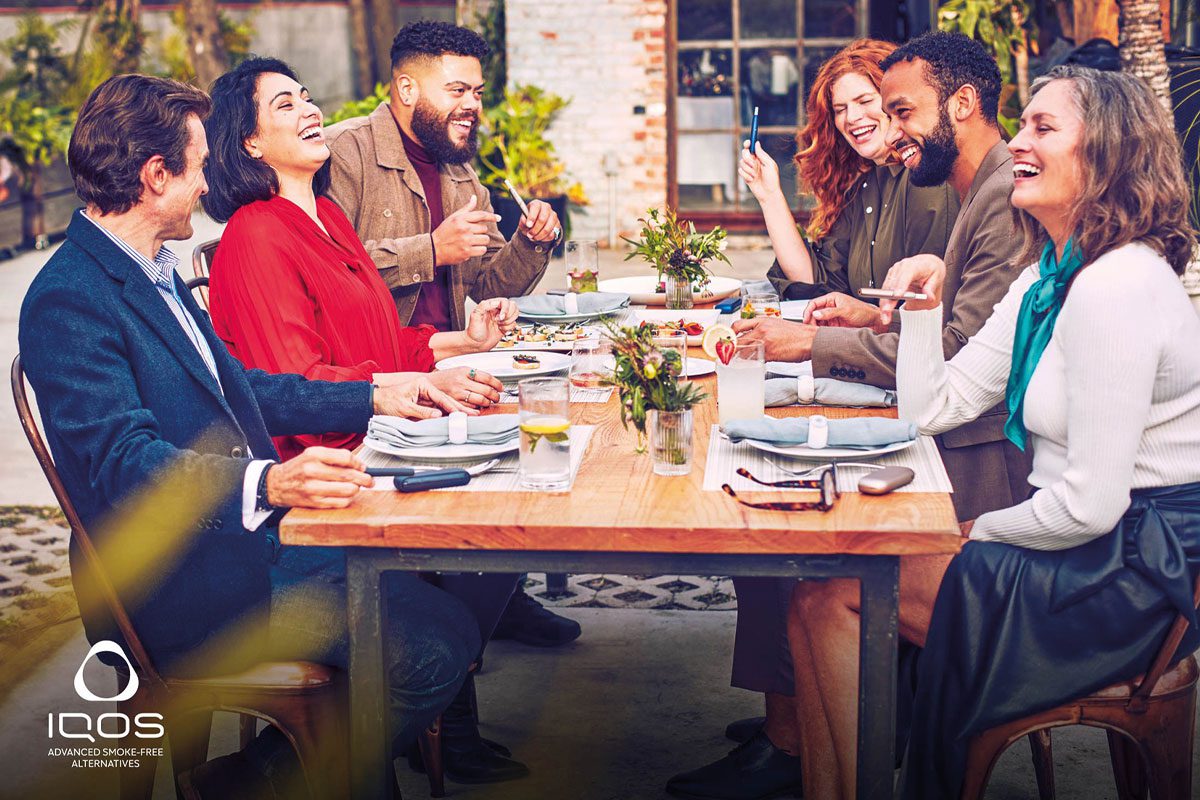 people sit around a dinner table smoking ecigarettes