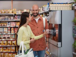 The time to prepare for DRS has arrived a man and woman put a plastic bottle into a DRS machine
