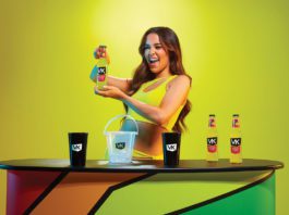 Vibrant new VK packaging a woman holds a bottle of VK alcopop in a neon yellow dress infront of a neon yellow background