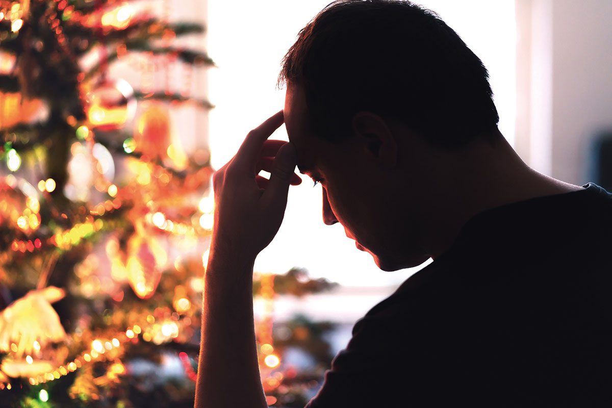 a man looks pensive infront of a christmas tree