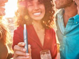 Phillip Morris Limited launch revamped IQOS smoke free devices a smiling woman holds an e-cigarette