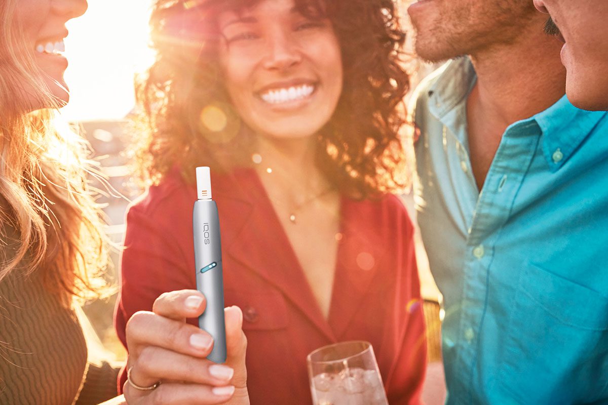 a smiling woman holds an e-cigarette