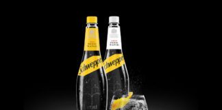 two bottles of schwepps tonic water and a glass on tonic with a lemon slice