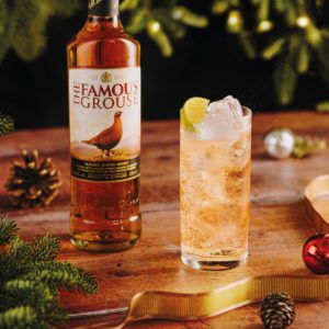 a bottle of the famous grouse whisky next to a whisky cocktail