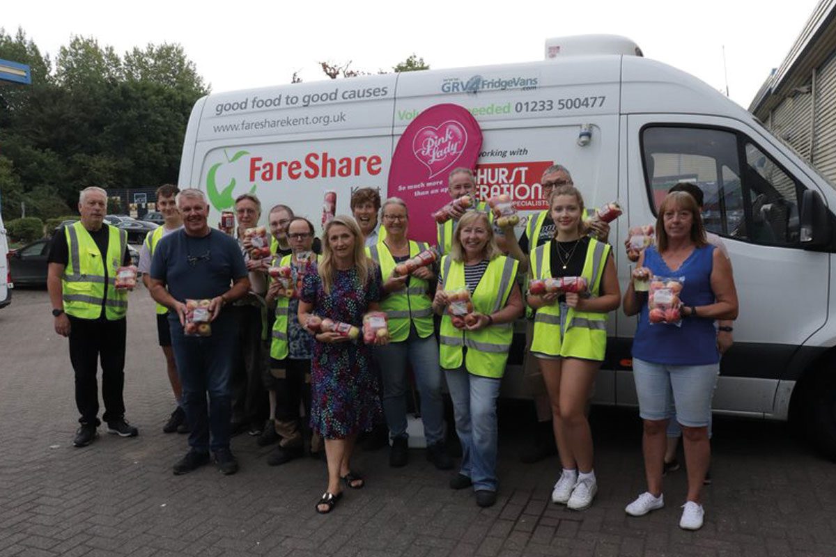 People stand infront of a Fareshare van holding pink lady apples