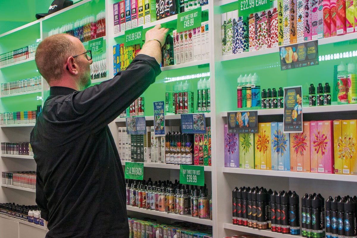 a person stocks the shelves of a vape store