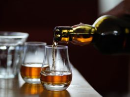 Raising a glass to malt whiskies two drams are poured from a whisky bottle