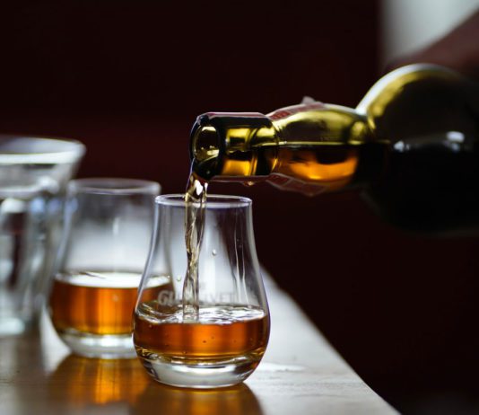 Raising a glass to malt whiskies two drams are poured from a whisky bottle