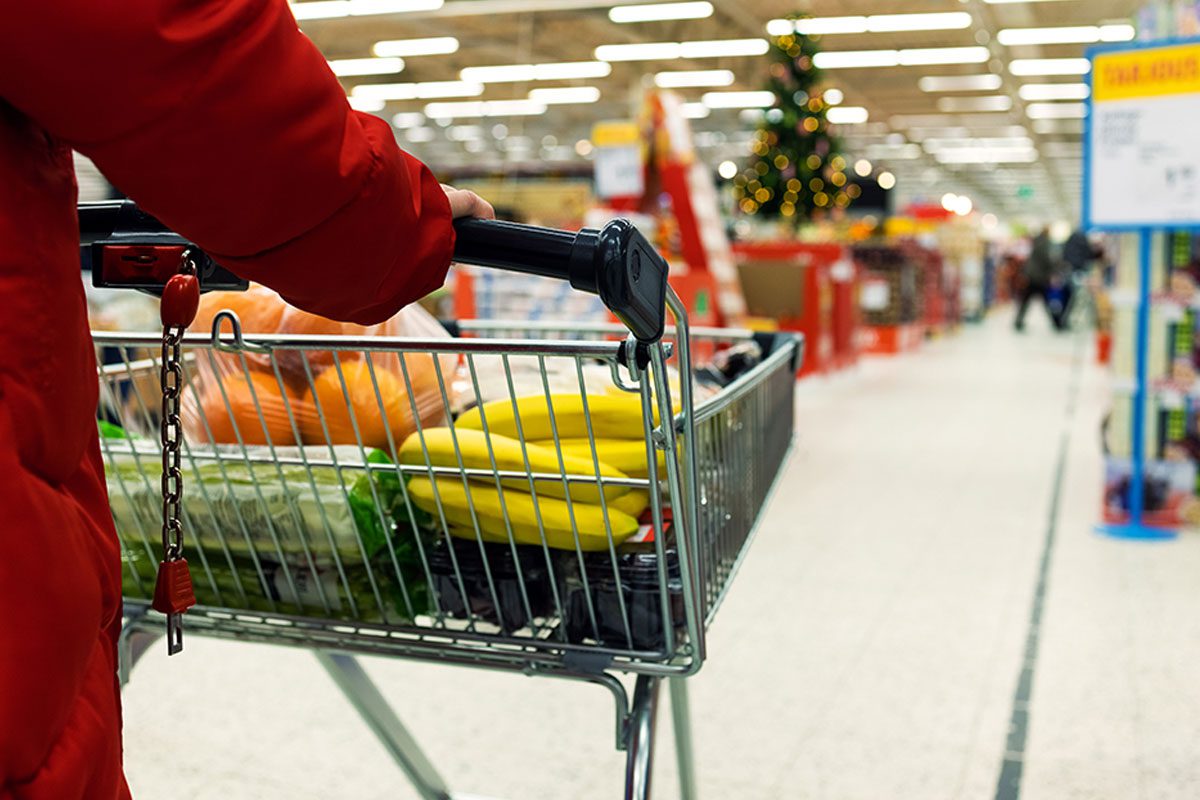 A shopper pushes a trolley or groceries in a store.