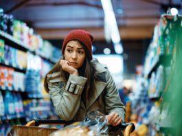 Retail recovery is fragile woman thinking in a grocery store
