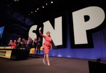 Nicola Sturgeon walking across stage with SNP in large letters