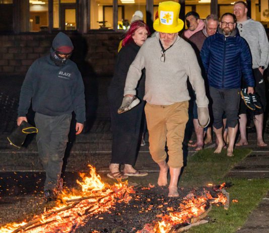 Flaming brave for charity Spar Scotland colleague walking across fire with a Marie Curie hat on