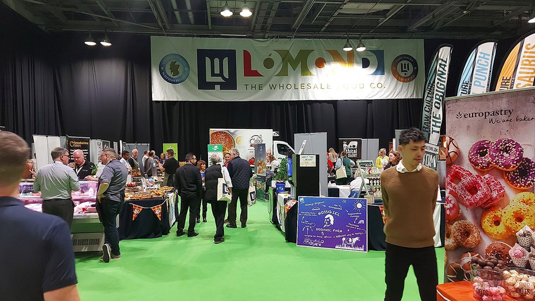 Lomond The Wholesale Food Co trade show shot showing a crowd of people at different stalls across the trades how floor.