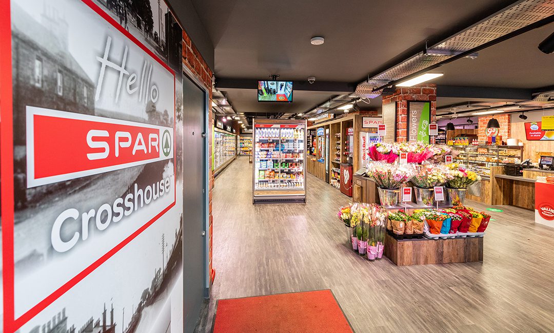 Interior shot of the Spar Crosshouse store featuring shelves of products as well as pictures of Crosshouse from the past.
