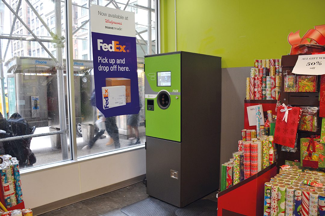 Reverse vending machine in the corner of a store against a green wall and window.