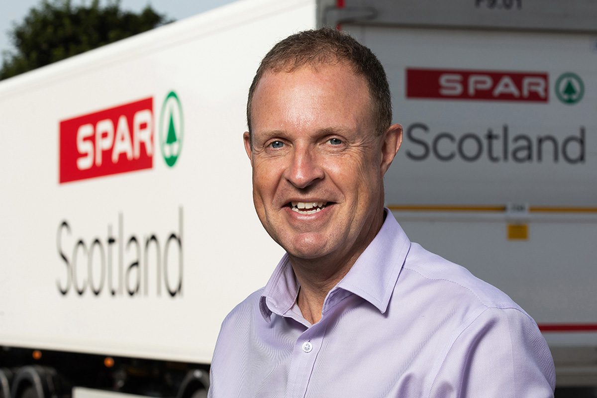 Colin McLean, chief executive at CJ Lang & Son, stands in front of a white HGV with Spar Scotland branding across it.