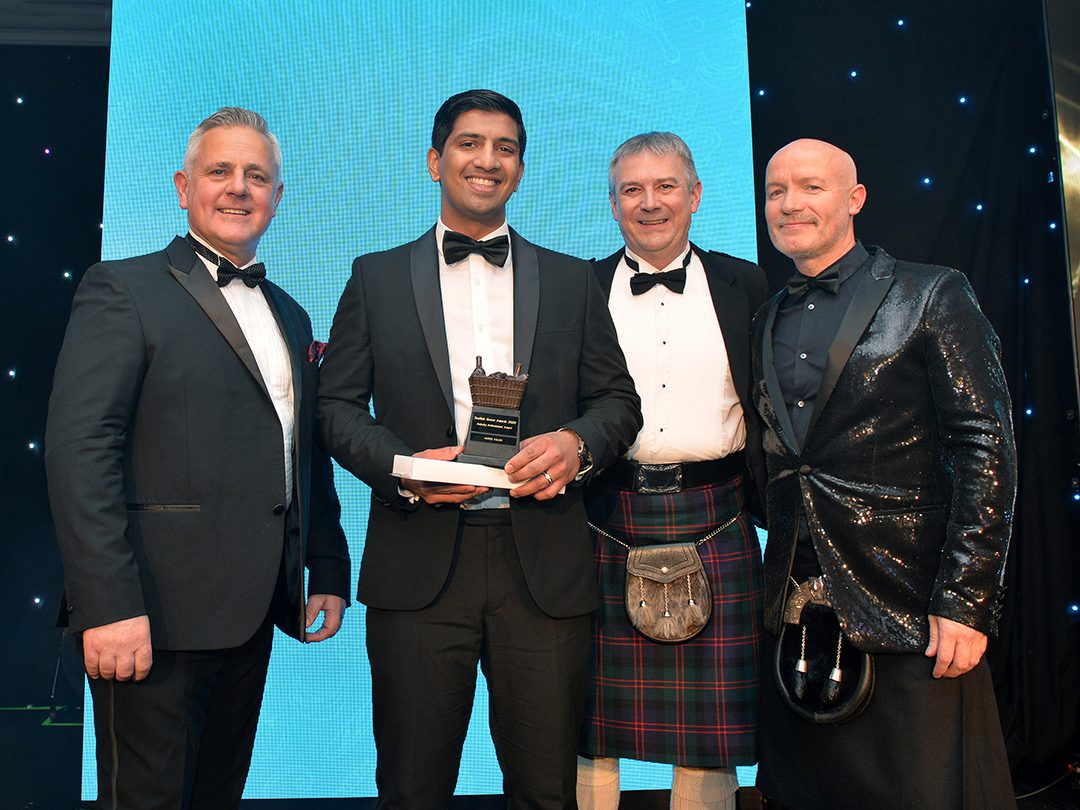 Harris Aslam is congratulated by Republic Technologies UK sales and marketing director Gavin Anderson, magazine editor Giles Blair and event host Craig Hill at the Scottish Grocer Awards 2022 in Glasgow.