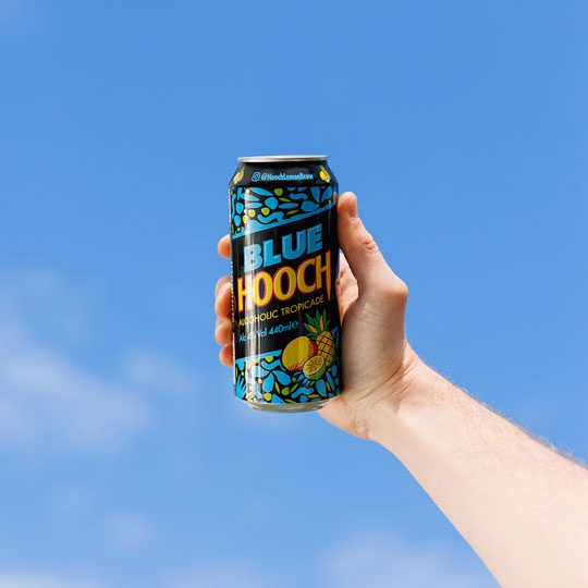 A person is holding a can of Blue Hooch with the sky in the background