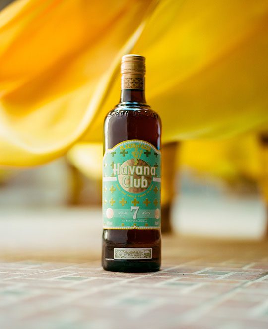 Bottle of the new limited edition Havana Club 7 rum with a yellow cloth behind it.