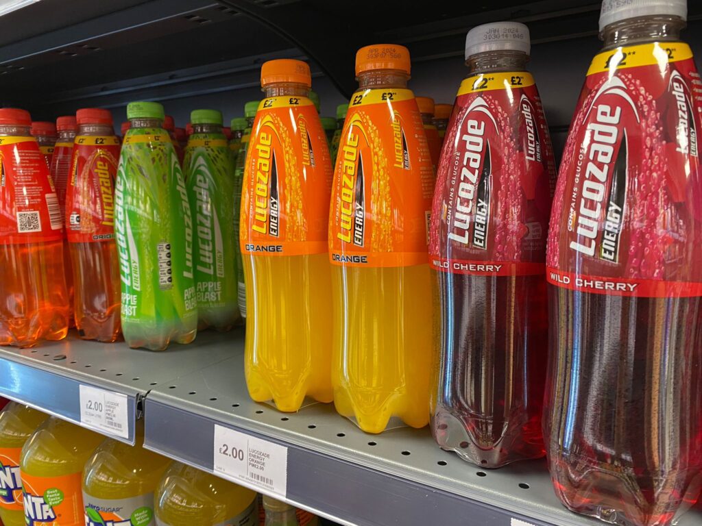 Bottles of Lucozade Energy on shop shelf.