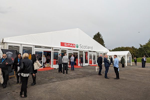 A white outdoor tradeshow tent for Spar Scotland with branding above the doors and multiple people standing outside.