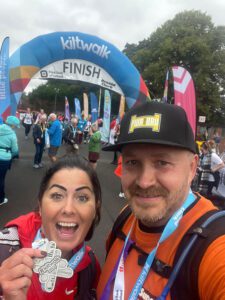 Christina Grant and Mark Graham stand together at the end of the Edinburgh Kiltwalk. Grant is holding a medal for the event.