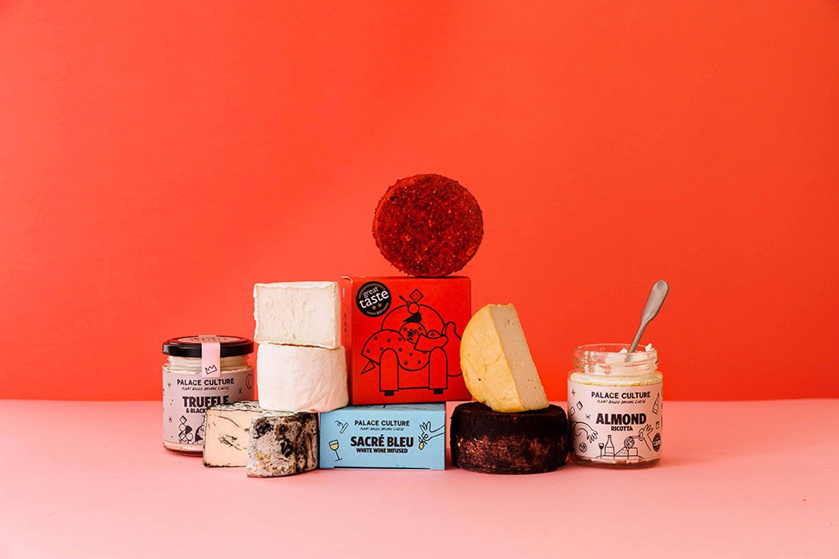 A range of plant-based cheese options from Palace Culture have been stacked together against a red background with a white surface.