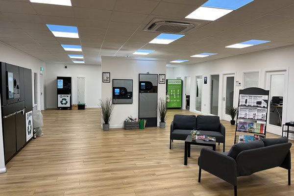 RVMSystems show room with a sitting area with couches and reading materials as well as different examples of reverse vending machines seen across the room.