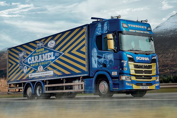 Tunnock's Dark Chocolate Caramel Wafer Biscuits branded HGV drives in the Scottish roads with a snowy mountain in the background.