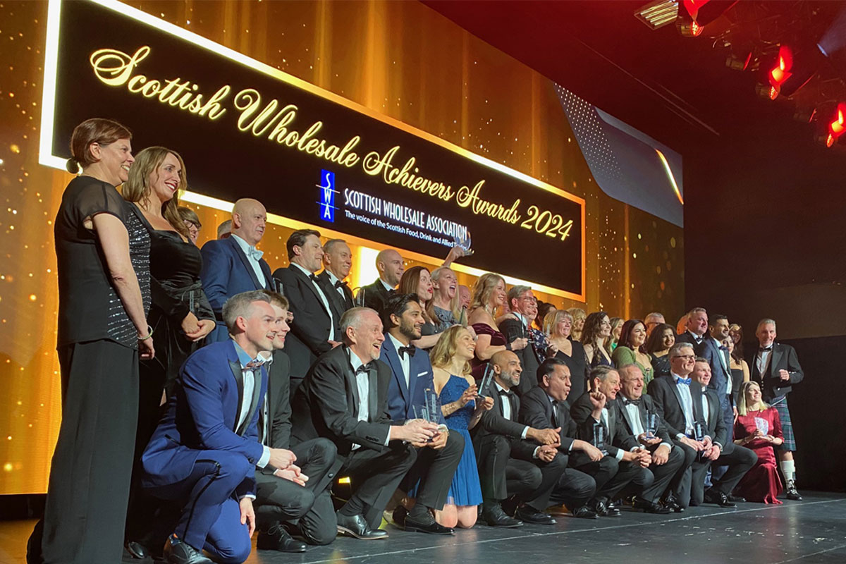 Winners stand together on the Scottish Wholesale Achievers Awards 2024 on a stage.