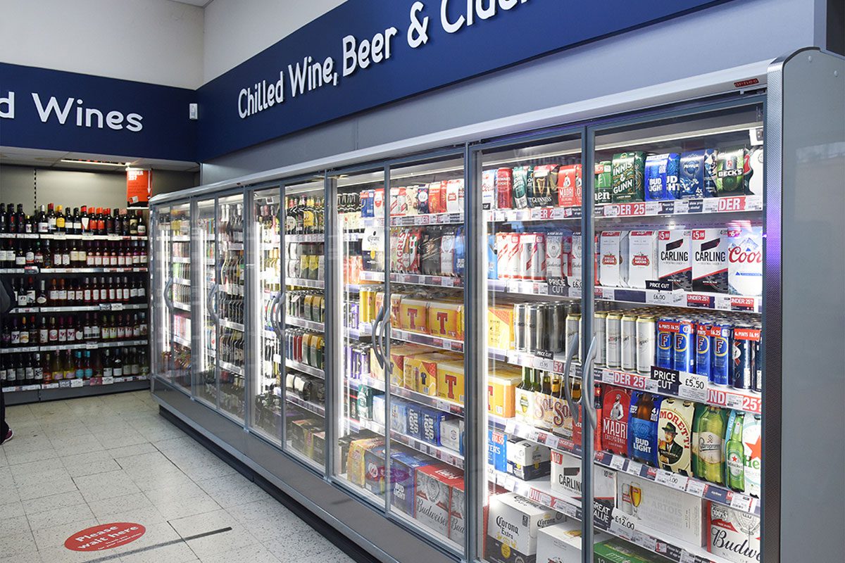 A shot of a convenience store's off-licence section including a range of chillers stocked with beer with wine options to the left of the image.