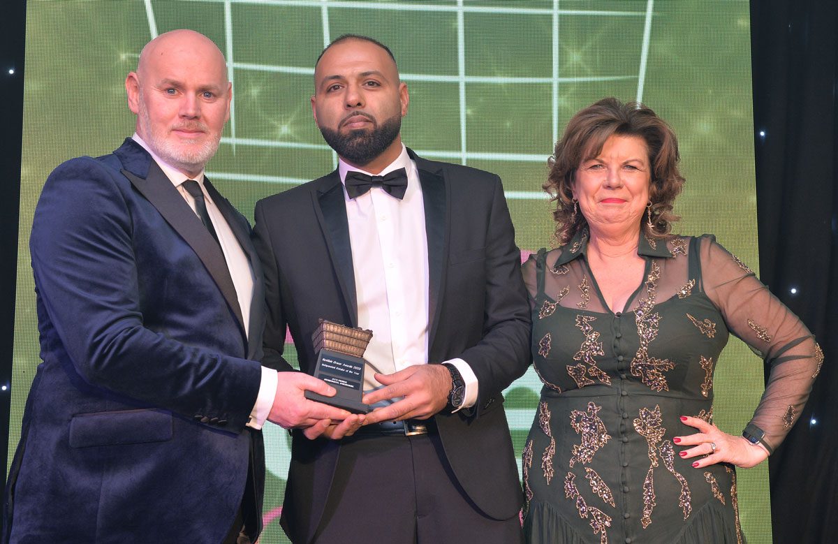 Shajaz Ali is congratulated by Booker Group retail development controller Barry Forbes and 2023 awards host Elaine C Smith.