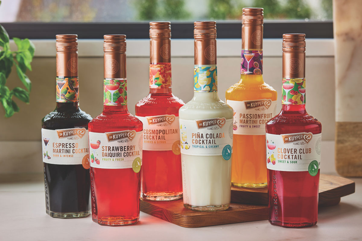 The new De Kuyper range of cocktails are lined up on a table with a window behind it.